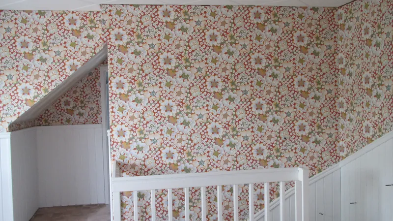 Trapphall med blommig tapet och vitt räcke